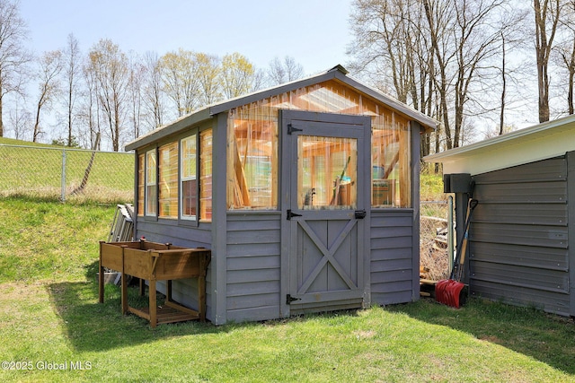 view of greenhouse with a yard and fence