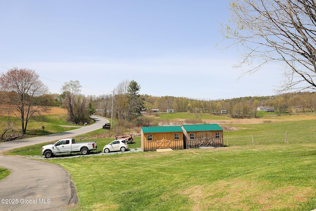 view of community with a lawn, fence, and an outdoor structure