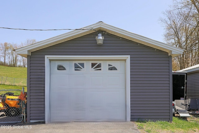 detached garage featuring fence and concrete driveway