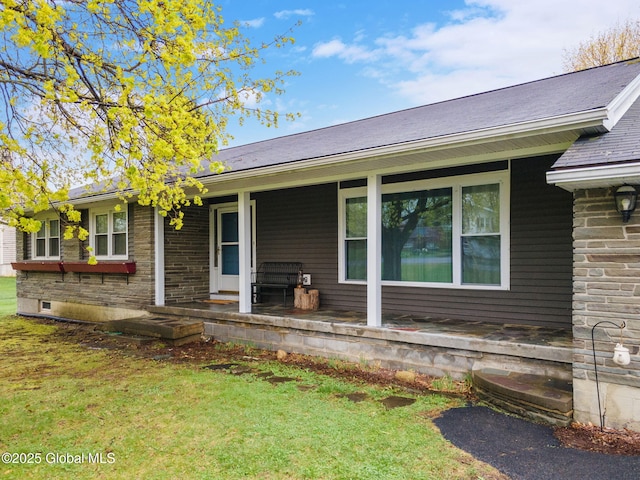 rear view of house featuring covered porch and a lawn