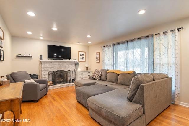living room with a brick fireplace, recessed lighting, and light wood-style floors