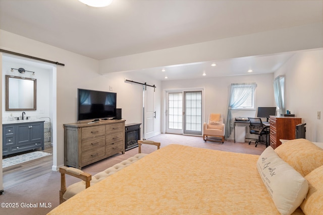 bedroom featuring a sink, recessed lighting, a barn door, and light colored carpet