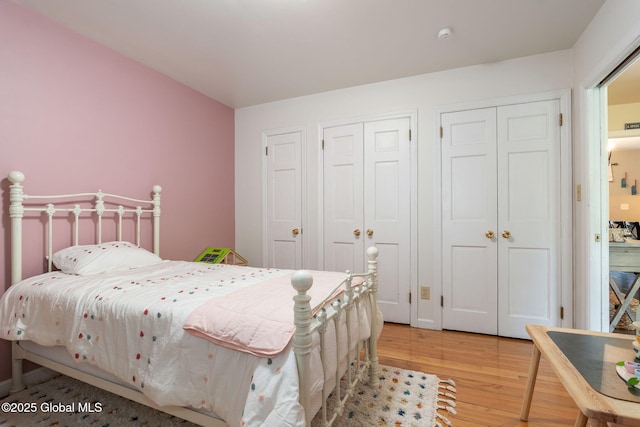 bedroom featuring multiple closets and light wood-type flooring