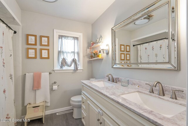 full bathroom with a sink, baseboards, toilet, and double vanity