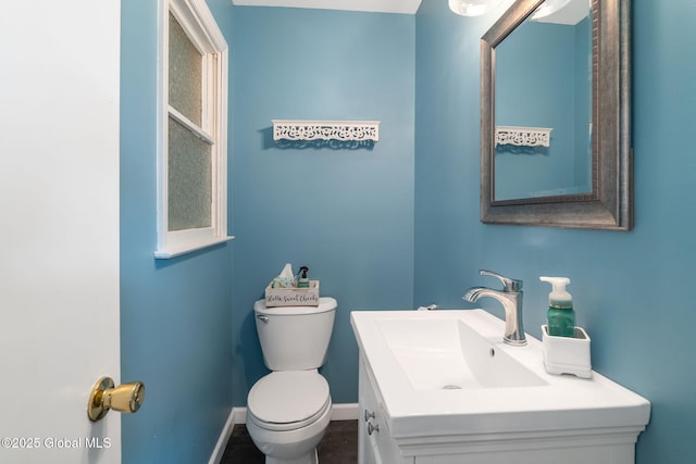 half bathroom with toilet, baseboards, and vanity
