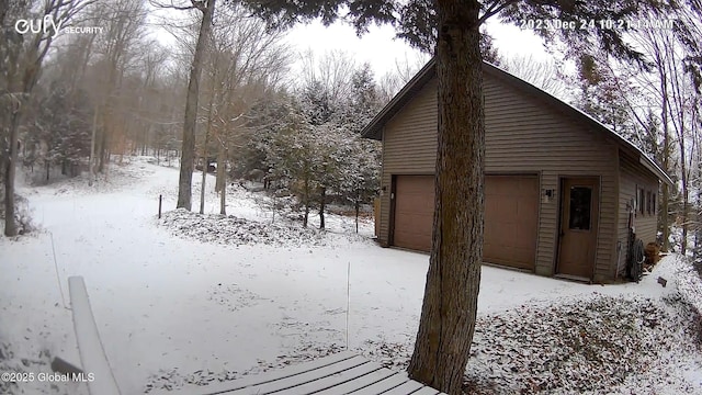 view of snowy exterior with a garage and an outbuilding