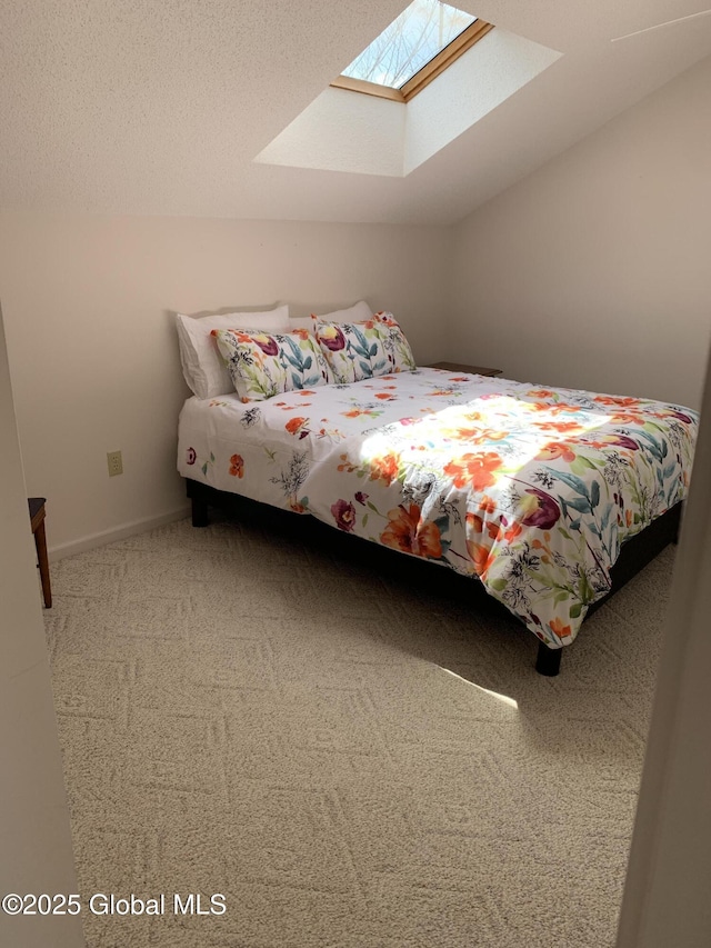 bedroom featuring baseboards, lofted ceiling with skylight, and carpet flooring