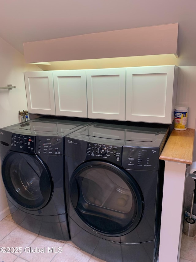clothes washing area with light tile patterned floors, cabinet space, and washing machine and clothes dryer