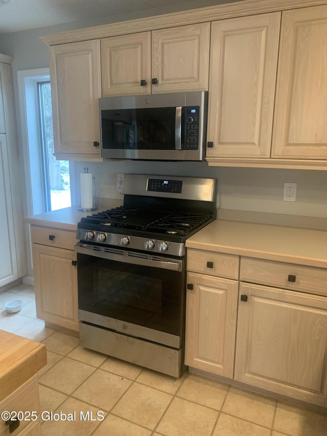 kitchen with light tile patterned floors, stainless steel appliances, and light countertops