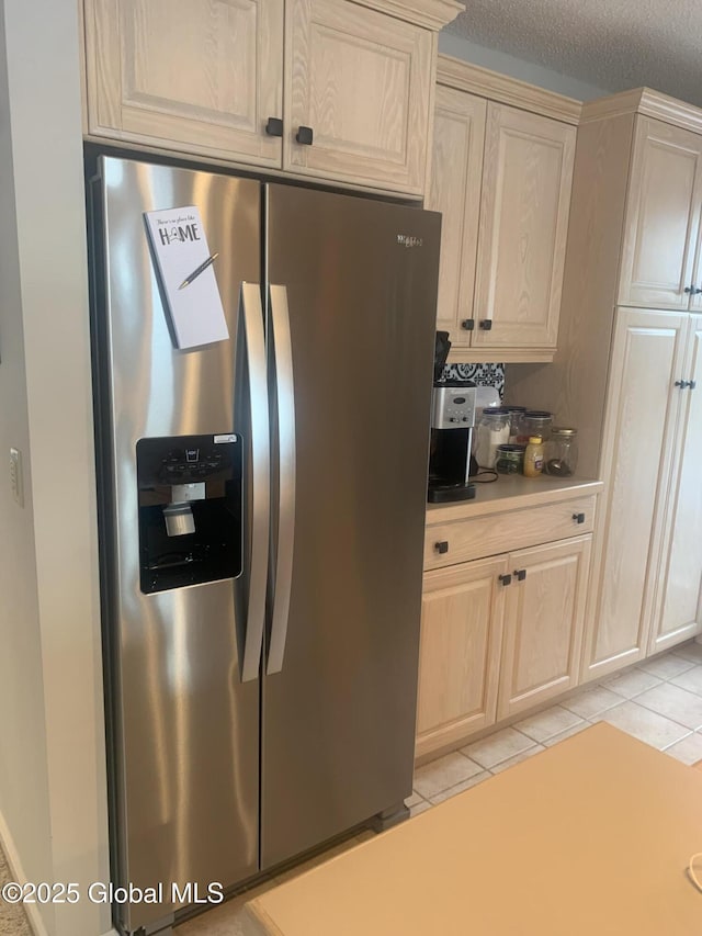 kitchen with stainless steel fridge, light tile patterned flooring, and light brown cabinets