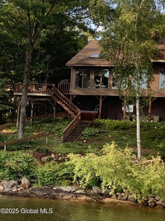 rear view of house featuring stairway and a deck with water view