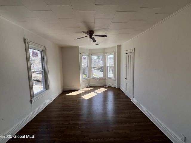 spare room featuring a ceiling fan, dark wood-style flooring, and baseboards