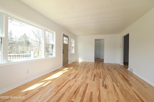 unfurnished living room with light wood-style floors, baseboards, and visible vents