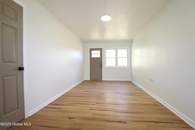 interior space featuring crown molding, light wood-style flooring, and baseboards