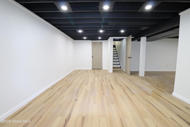 finished basement featuring baseboards, wood finished floors, and stairway