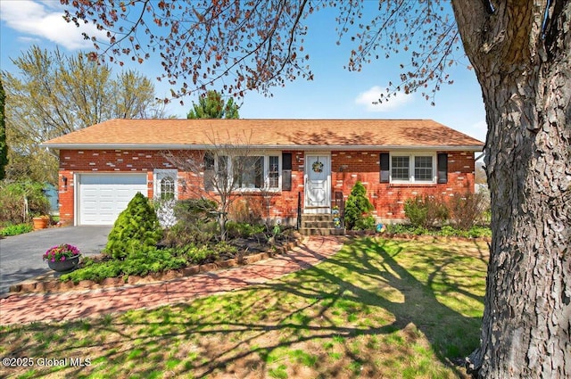 ranch-style home featuring an attached garage, a front lawn, aphalt driveway, and brick siding