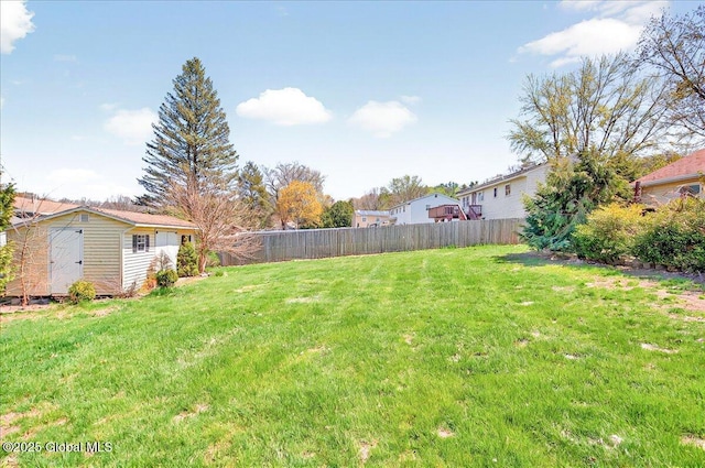 view of yard featuring an outdoor structure, fence, and a storage shed
