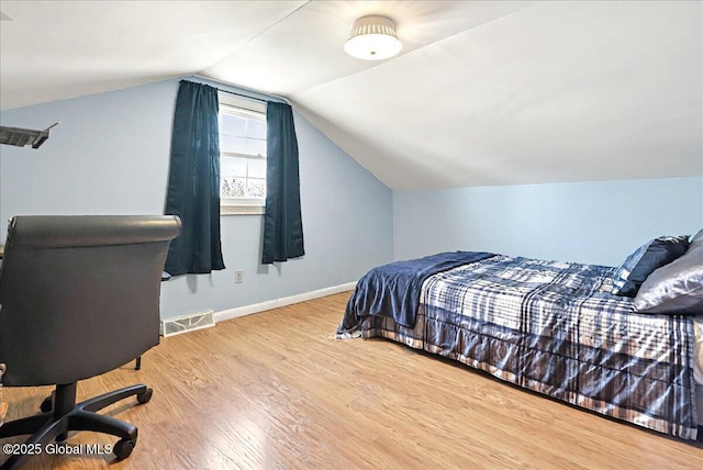 bedroom with baseboards, visible vents, wood finished floors, and lofted ceiling