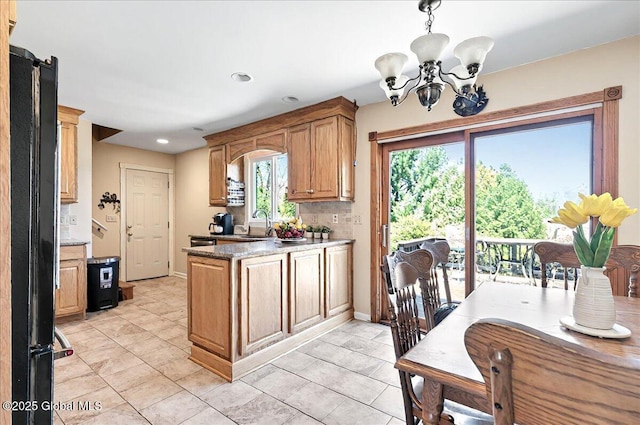 kitchen featuring freestanding refrigerator, a peninsula, a chandelier, recessed lighting, and light tile patterned flooring