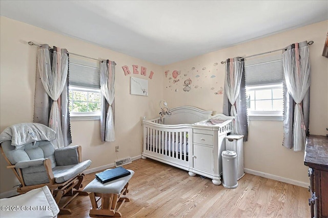 bedroom featuring visible vents, baseboards, multiple windows, and light wood-type flooring