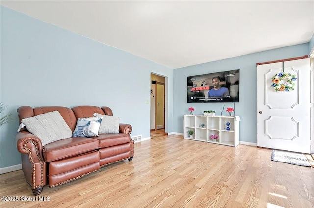 living room featuring baseboards, visible vents, and wood finished floors