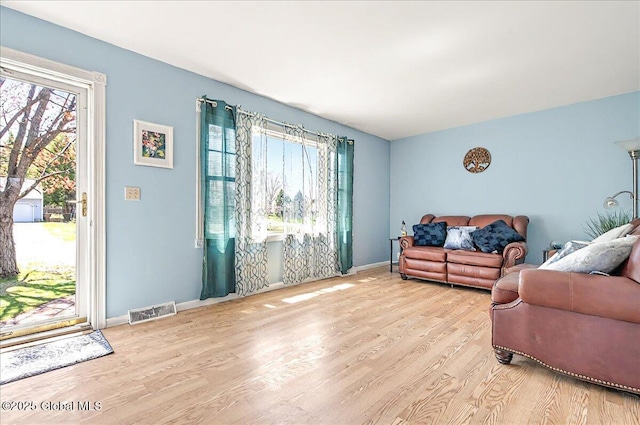 living area featuring baseboards, visible vents, plenty of natural light, and wood finished floors