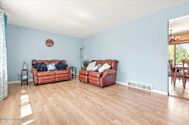 living area featuring baseboards, light wood-type flooring, and visible vents