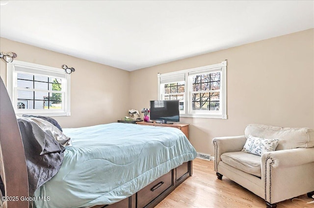 bedroom featuring baseboards, light wood-style flooring, and visible vents