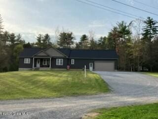 ranch-style house featuring a garage, dirt driveway, and a front lawn