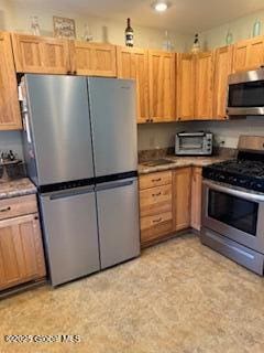 kitchen with a toaster, appliances with stainless steel finishes, and light brown cabinets