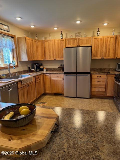 kitchen with recessed lighting, dark countertops, appliances with stainless steel finishes, and a sink