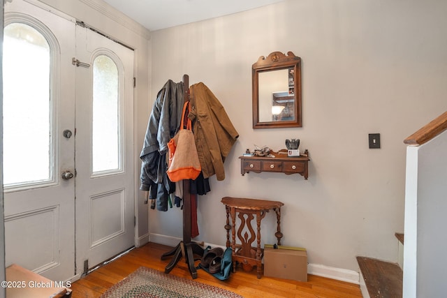 foyer entrance featuring baseboards, wood finished floors, and stairway