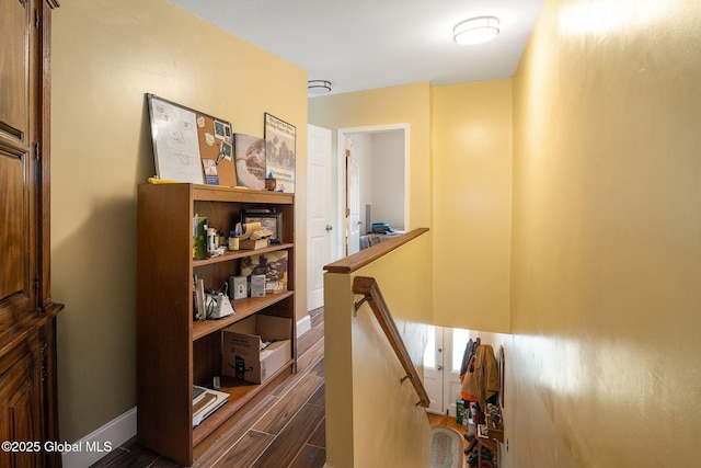 hall with dark wood-style flooring and an upstairs landing