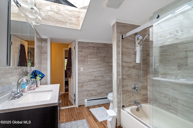 full bathroom featuring vanity, toilet, tile walls, bath / shower combo with glass door, and a baseboard heating unit