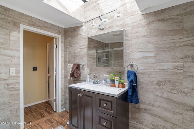 bathroom featuring wood tiled floor, a skylight, vanity, baseboards, and ornamental molding