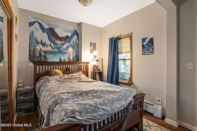 bedroom featuring baseboards, a baseboard heating unit, and wood finished floors