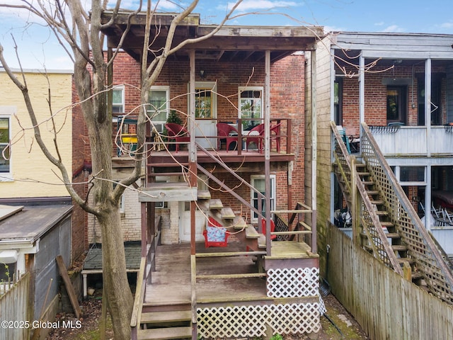back of house with brick siding, a wooden deck, and stairs