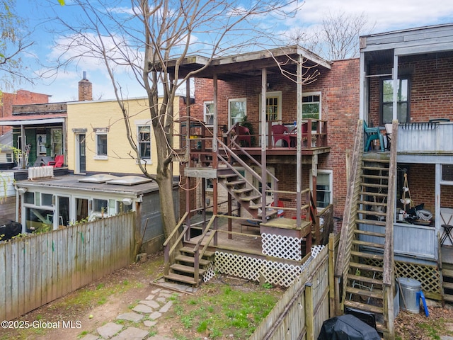 back of property with brick siding, a fenced backyard, stairway, and a deck