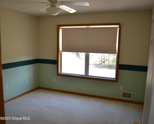 carpeted empty room featuring visible vents, ceiling fan, and baseboards