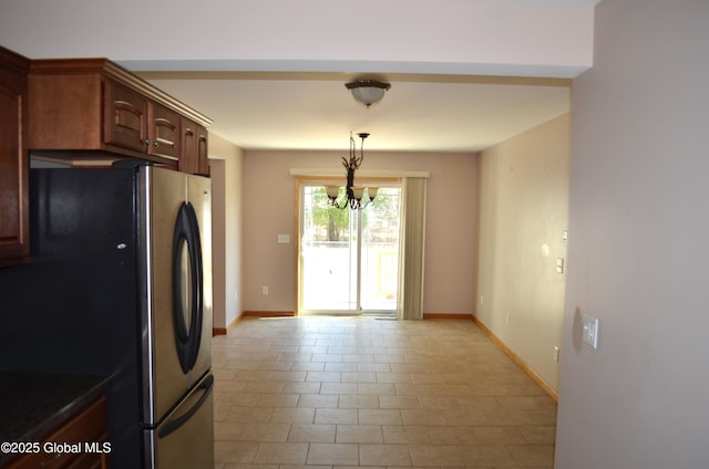 kitchen featuring pendant lighting, a notable chandelier, freestanding refrigerator, and baseboards