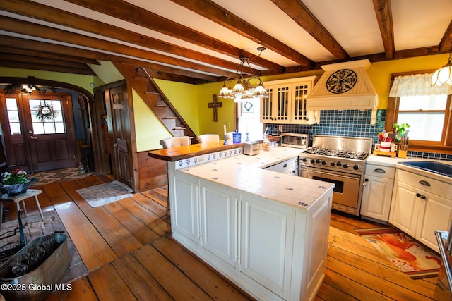 71 S Rd, Hampton, NY 12887 - kitchen featuring stainless steel appliances, custom range hood, tile counters, hardwood / wood-style flooring, and glass insert cabinets