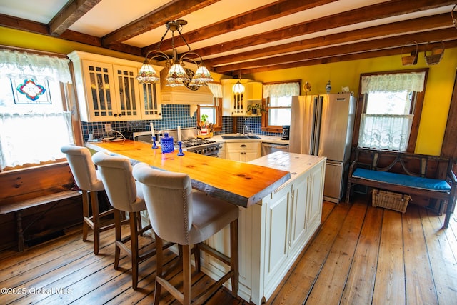 71 S Rd, Hampton, NY 12887 - kitchen featuring appliances with stainless steel finishes, butcher block countertops, backsplash, beam ceiling, and glass insert cabinets