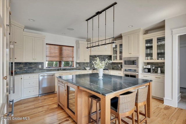 20 Oak Ridge Blvd, Saratoga Springs, NY 12866 - kitchen with a kitchen island, stainless steel appliances, decorative backsplash, and a kitchen bar