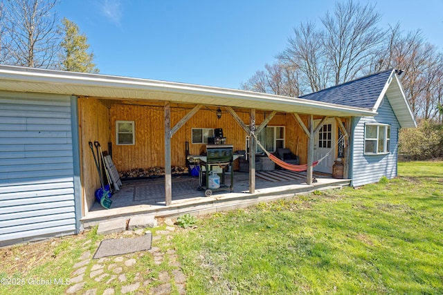 exterior space with a shingled roof and a yard