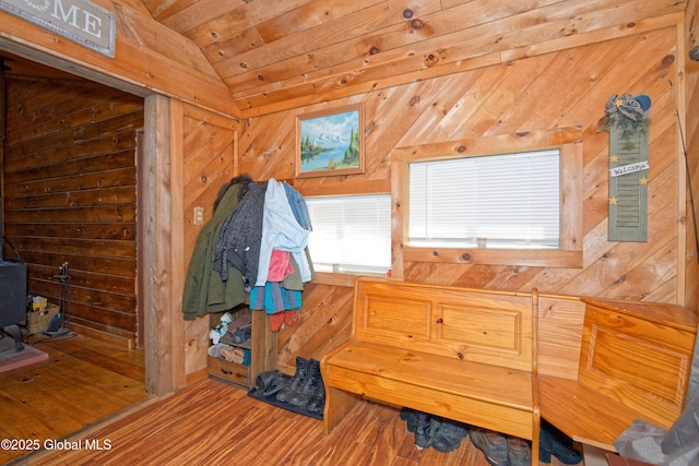 mudroom with a wood stove, wooden walls, wood finished floors, and vaulted ceiling