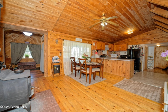 kitchen with light wood-type flooring, a peninsula, black refrigerator with ice dispenser, and a healthy amount of sunlight