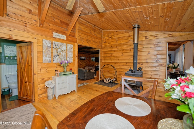 living room featuring a wood stove, wood walls, hardwood / wood-style floors, vaulted ceiling, and wood ceiling