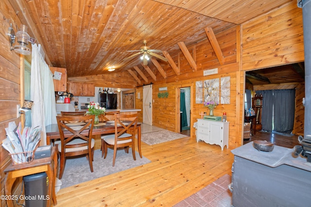 dining room with wooden walls, vaulted ceiling, wood ceiling, and light wood-type flooring