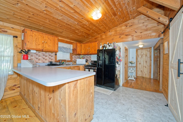 kitchen featuring black fridge, stainless steel gas stove, a peninsula, vaulted ceiling, and wood ceiling