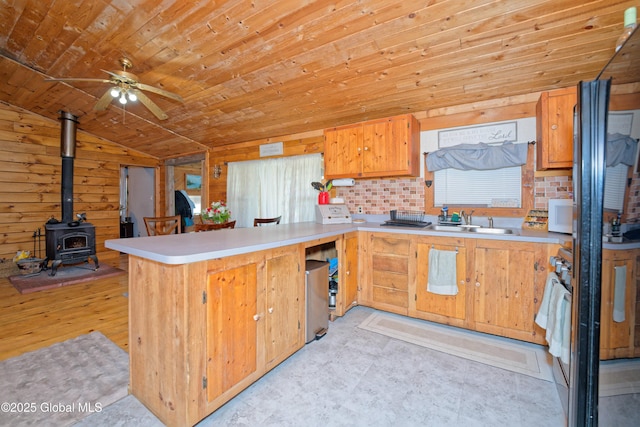 kitchen featuring a sink, a peninsula, wood ceiling, a ceiling fan, and vaulted ceiling